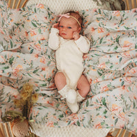 Baby lying on Wattle Floral Organic Muslin Wrap